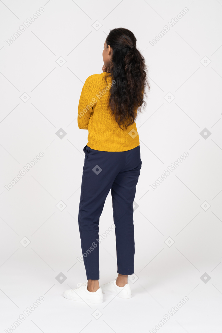 Rear view of a girl in casual clothes standing with crossed arms