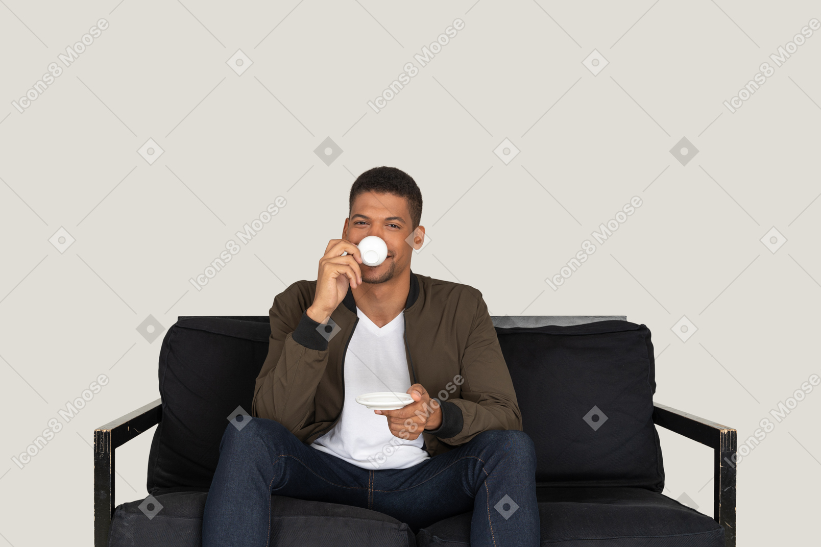 Vista frontale di un giovane sognatore seduto su un divano mentre beve caffè