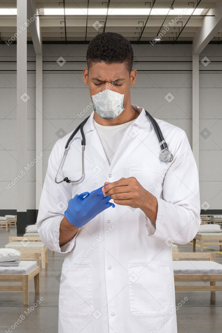 A tired doctor taking off his gloves