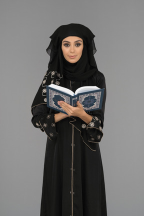 A covered muslim woman holding the quran