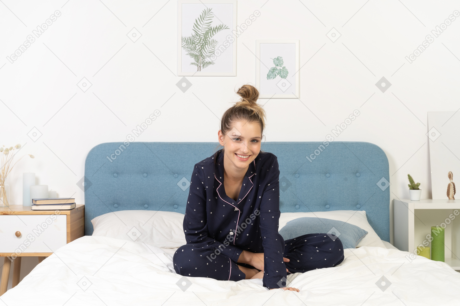 Front view of a smiling young woman in pajamas staying in bed