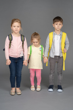 Bambini con zaini isolati su sfondo grigio