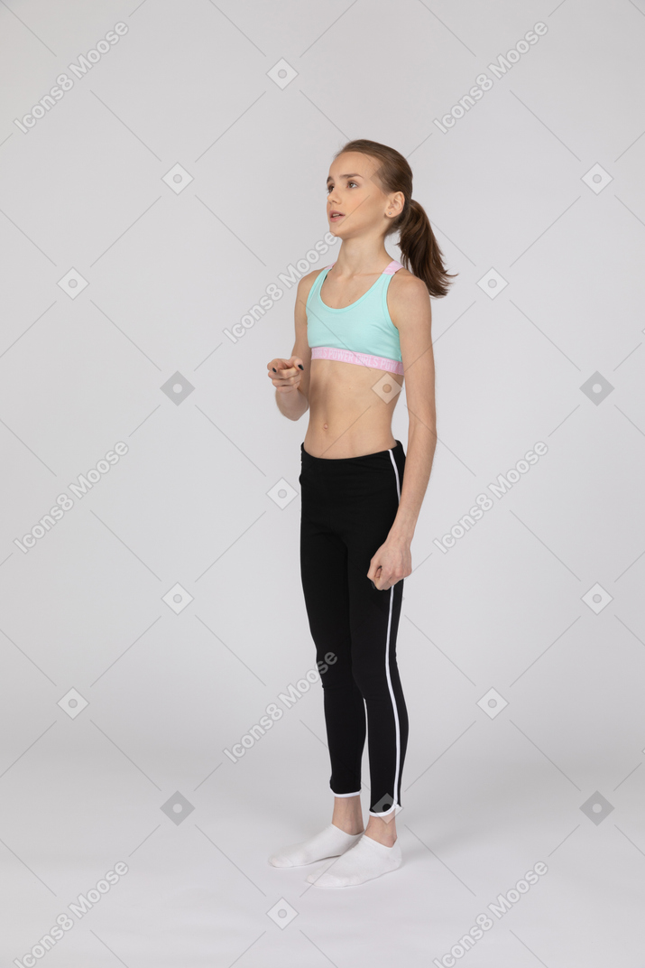 Three-quarter view of a teen girl in sportswear raising hand and looking aside