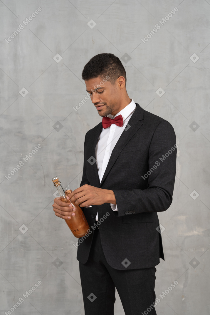 Homem de terno completo abrindo uma garrafa de champanhe