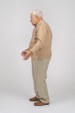 Vista lateral de um velho em roupas casuais em pé com os braços estendidos