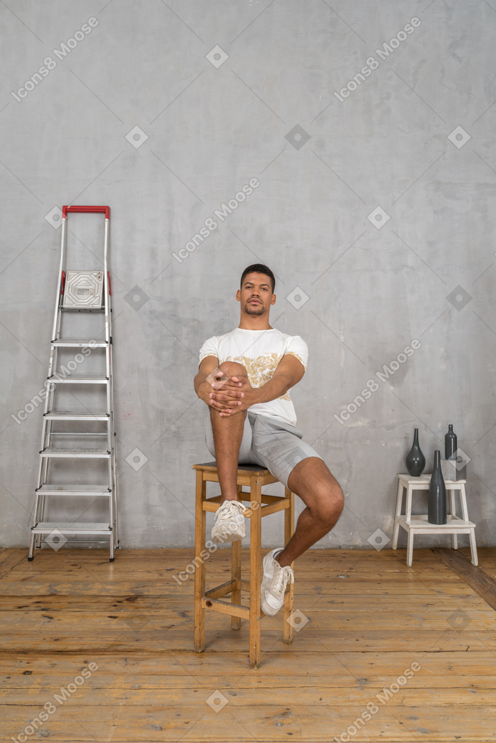 Junger mann, der mit den händen auf seinem knie sitzt
