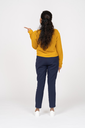 Rear view of a girl in casual clothes pointing with a finger