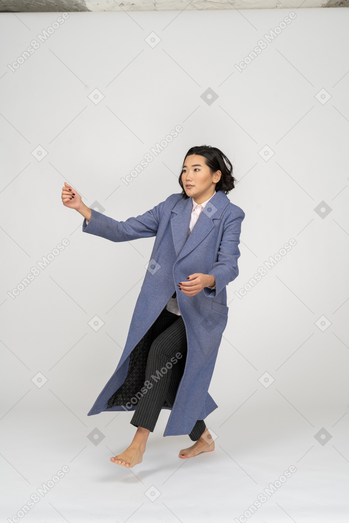 Young woman in coat bent on one leg