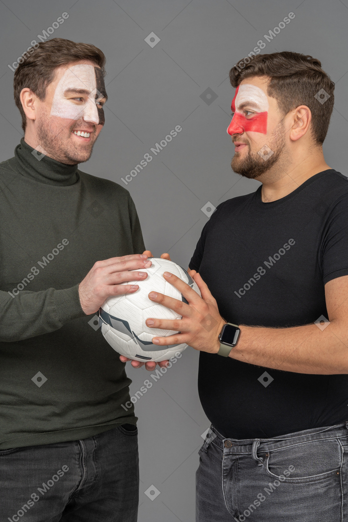 Two male football fans both holding the ball