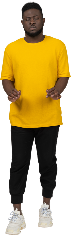 Вид спереди на молодого темнокожего мужчину в желтой футболке, протягивающего руки доу