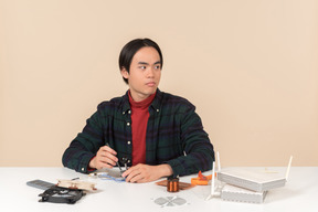 An asian geek guy in a dark checkered shirt, working with computer details