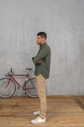 Side view of a man standing with crossed arms looking lost in thought