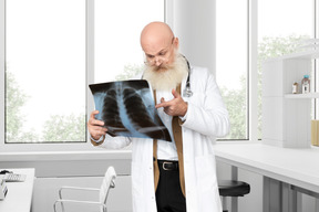 A man in a white lab coat is looking at a x - ray
