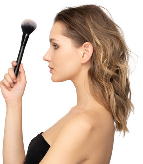 Side view of a sensual young woman holding a make-up brush