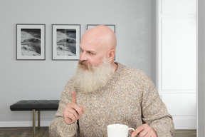 A man with a beard sitting at a table with a cup of coffee