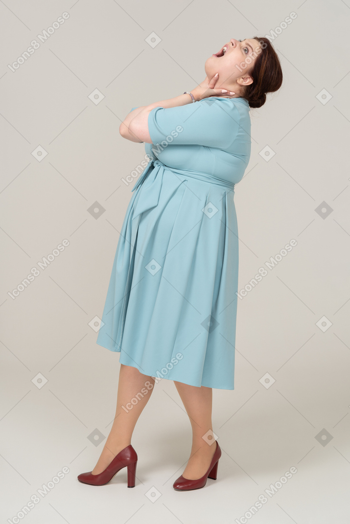 Vista laterale di una donna in abito blu che si soffoca