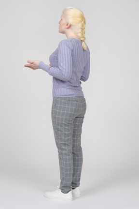 Three-quarter back view of a young woman explaining and gesturing