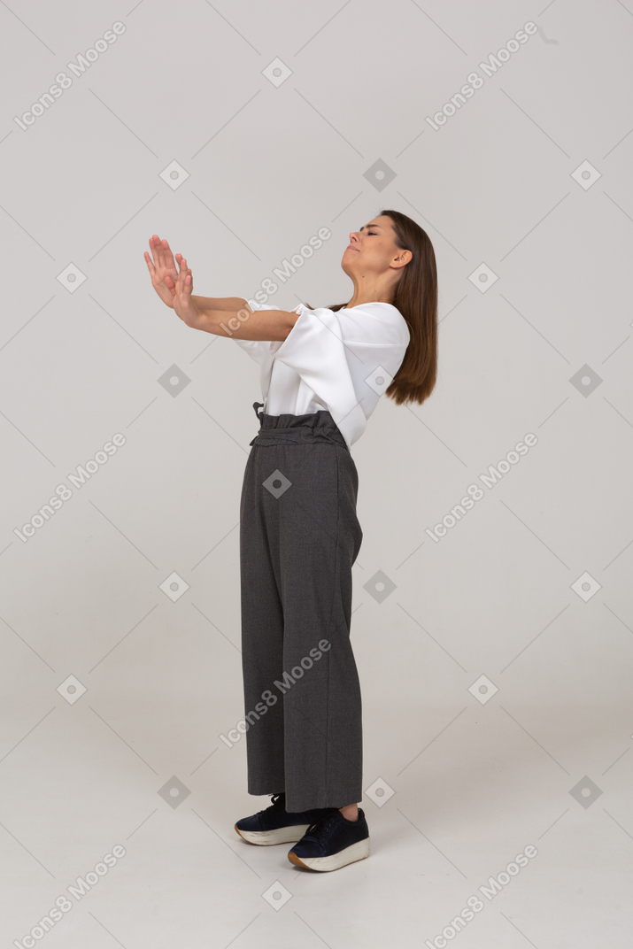 Side view of an unwilling young lady in office clothing outstretching arm