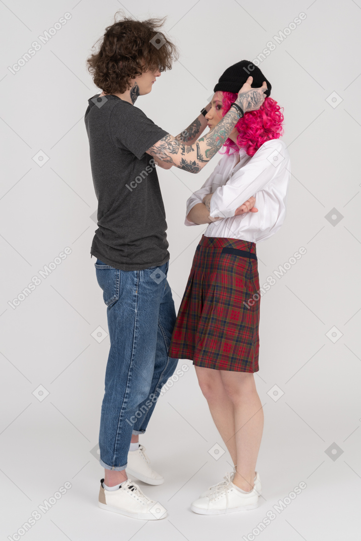 一个年轻的男性，把他的帽子放在她的女朋友的侧视图