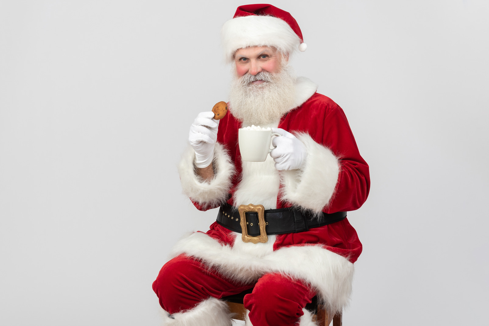 Positive santa claus drinking tea and eating cookie