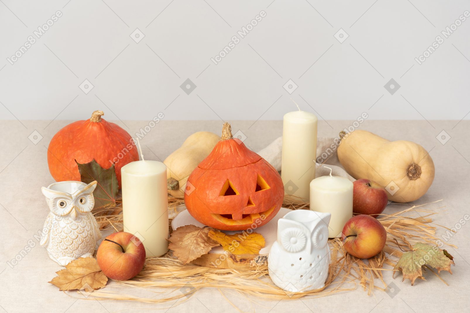 Abóboras esculpidas, figuras de corujas, velas e maçãs vermelhas