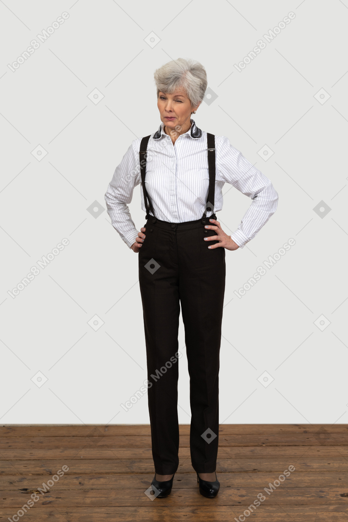 Corpo inteiro de uma mulher idosa em suspensórios colocando as mãos nos quadris piscando
