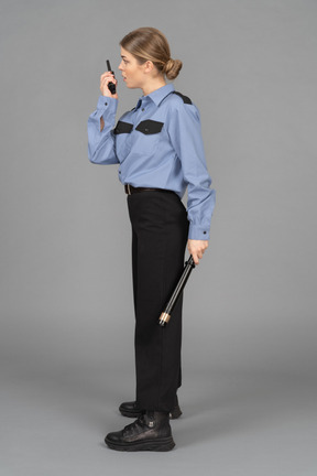 Female security guard with a baton speaking on the radio