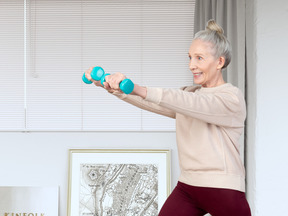 A woman is doing exercises with two blue dumbbells