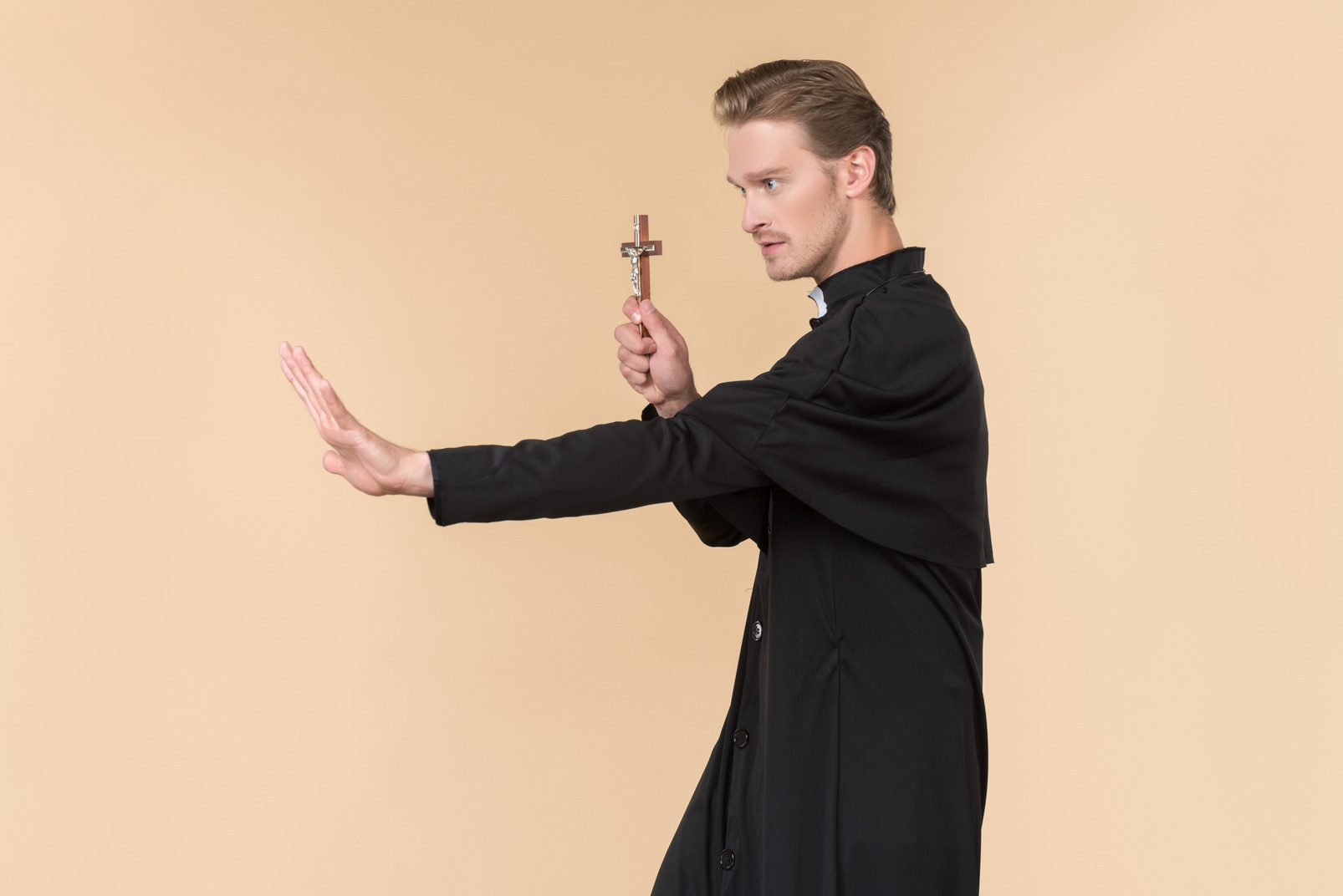 Catholic priest standing in profile and holding cross
