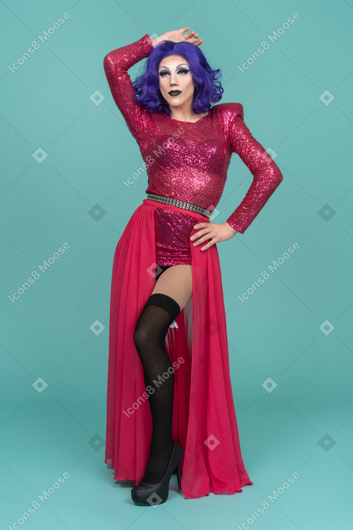Drag queen in rosa kleid posiert mit einer hand auf der hüfte und der anderen auf dem kopf