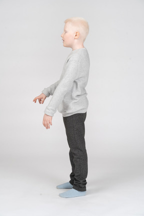 Vista lateral de um menino de pé e gesticulando