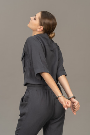Vista posteriore di tre quarti di una giovane donna sofferente in tuta che indossa le manette