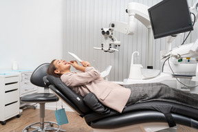 Pleine longueur d'une patiente allongée sur une chaise médicale et regardant dans le miroir