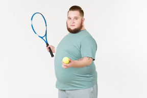 Big guy in sportswear holding tennis racket and tennis ball