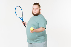 Tipo grande en ropa deportiva con raqueta de tenis y pelota de tenis