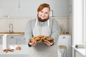 A man holding a plate of cookies in a kitchen