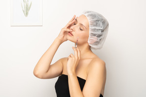 Young woman with syringe touching her face