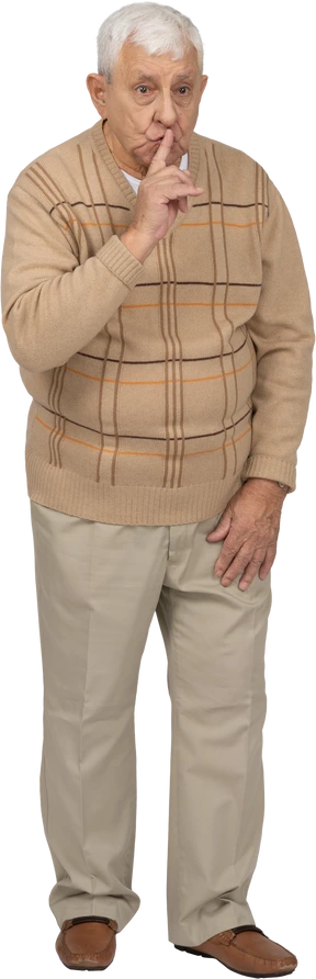 Front view of an old man in casual clothes showing silence sign