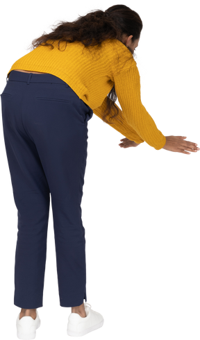 Rear view of a girl in casual clothes bending down with extended arms
