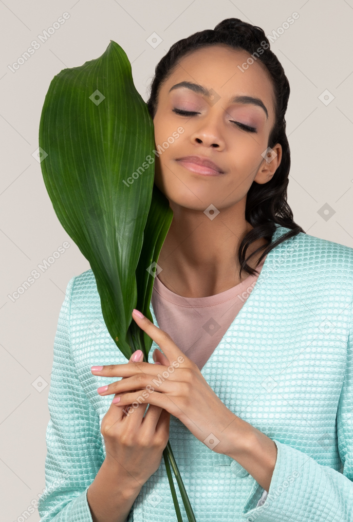 Mujer joven sosteniendo una gran hoja verde