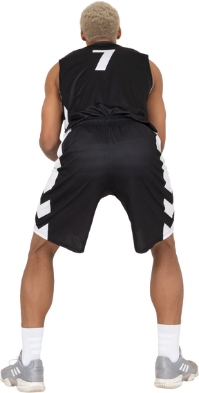 Vista traseira de um jovem jogador de basquete segurando uma bola