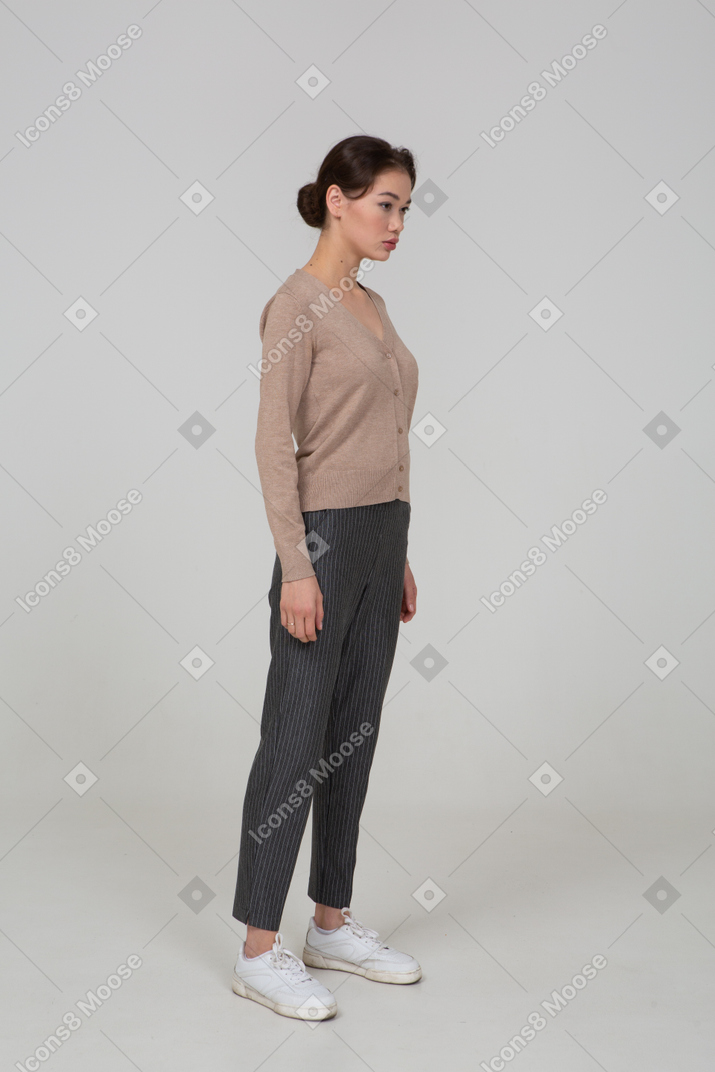Vista di tre quarti di una giovane donna triste in pullover e pantaloni