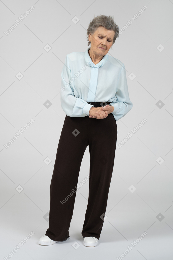 Front view of an old woman looking down sadly with clasped hands