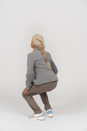 Back view of an old lady in suit squatting