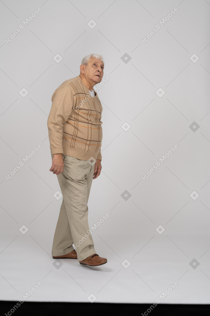 Вид сбоку на впечатленного старика в повседневной одежде, смотрящего вверх