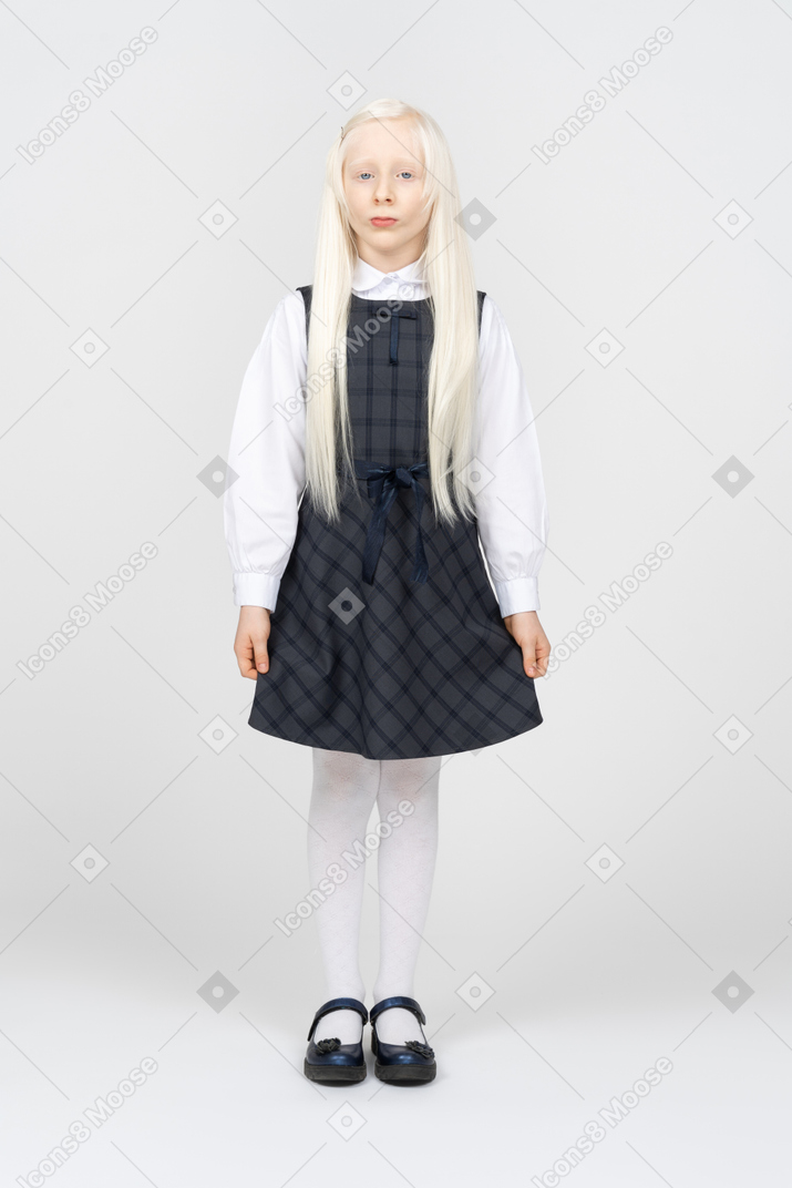 Schoolgirl looking serious while standing with arms at sides