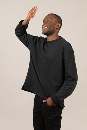 Side view of a smiling young man raising his arm