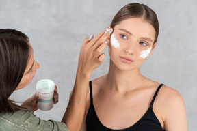 Young woman receiving skin treatment by beautician