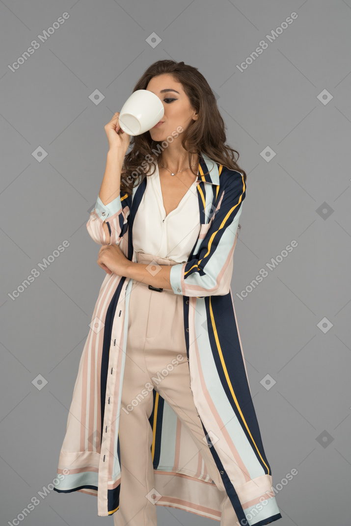 Pretty young woman drinking from a white cup