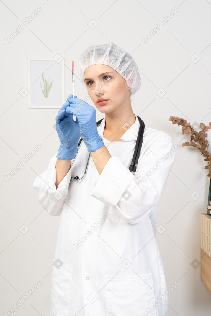 Vista frontal de una joven doctora sosteniendo una jeringa